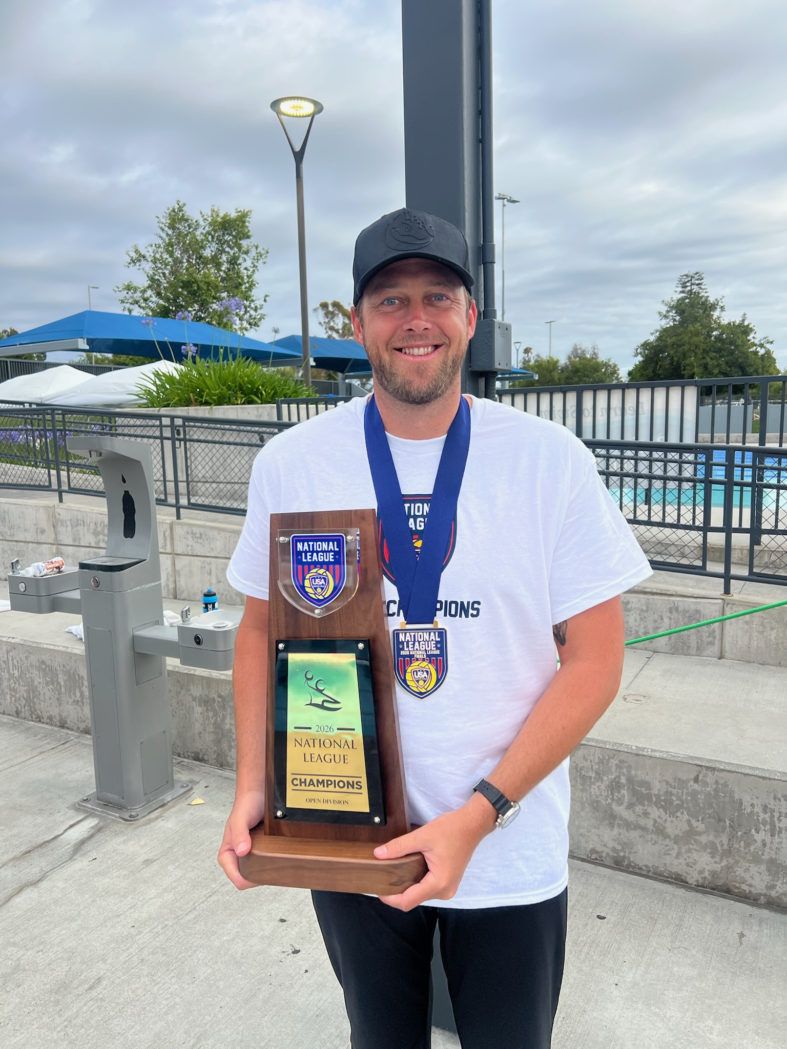 Invictus Aquatics coach with 2026 National League Champions trophy